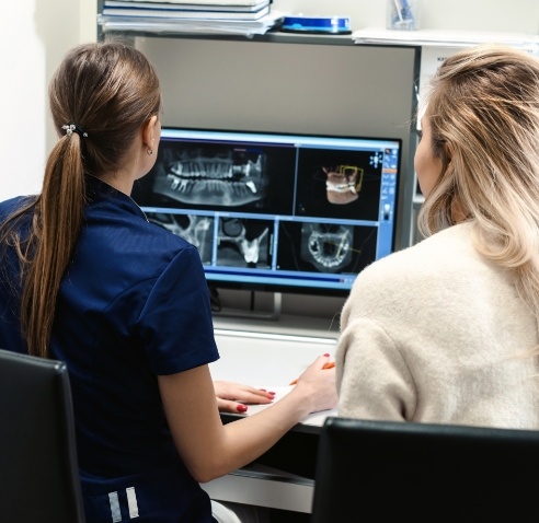 Dental team member showing a patient x rays of teeth on computer