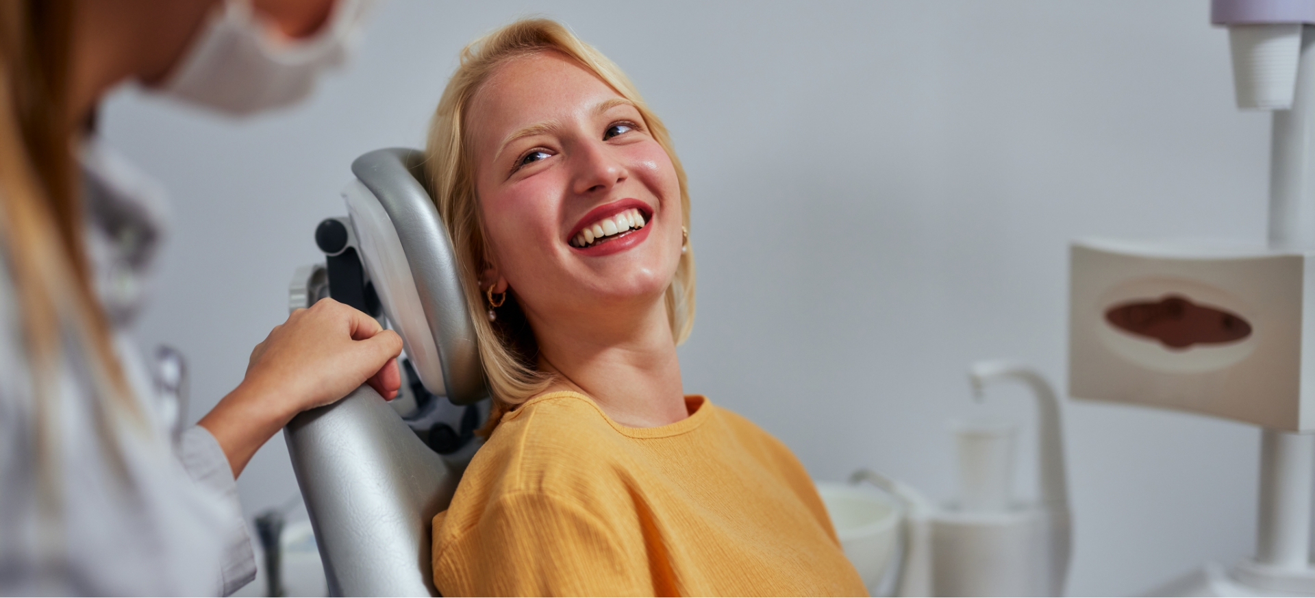 Blonde woman in yellow sweater smiling at her dentist