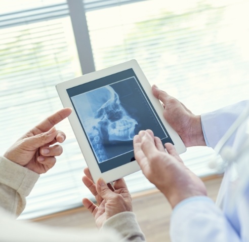 Two dentists looking at tablet with x ray of skull