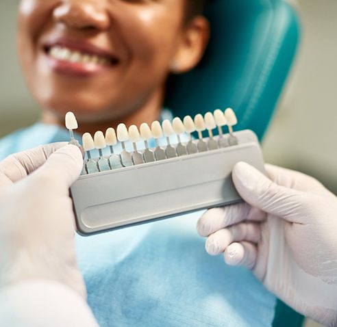 Dentist with white gloves selecting shade of veneer