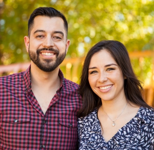 Man and woman smiling with autumn trees in background