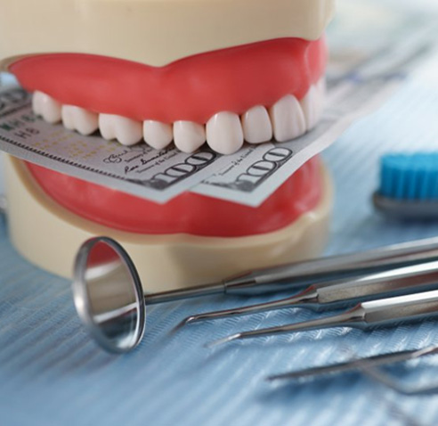 Dental model biting down on 100 dollar bills