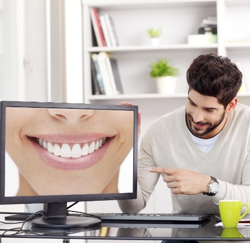 Man pointing to computer screen showing smile with flawless teeth