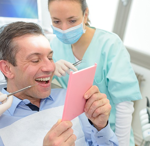 a patient smiling and admiring his new dental crown