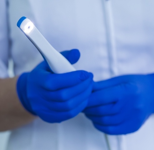 Dental team member holding a thin white intraoral camera