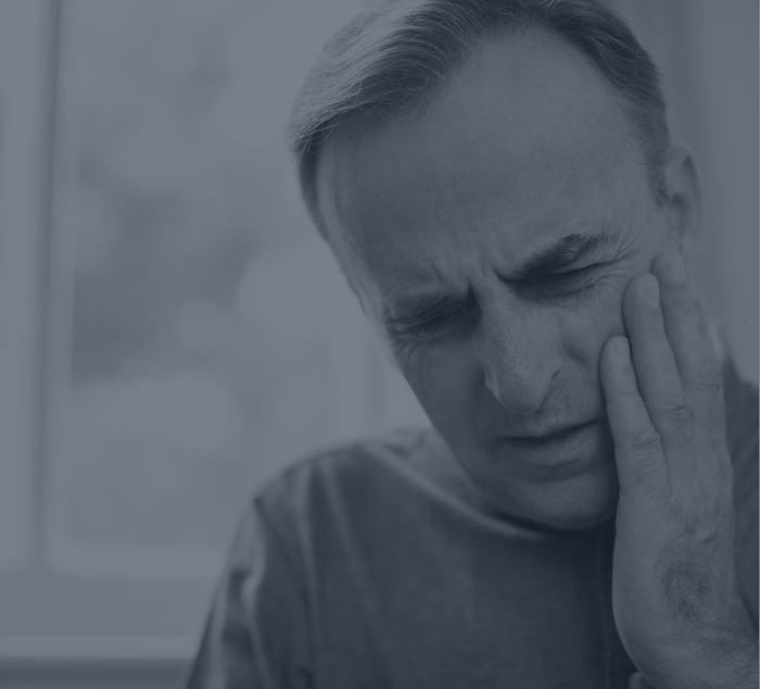 Man holding his cheek in pain and needing emergency dentist in Parker