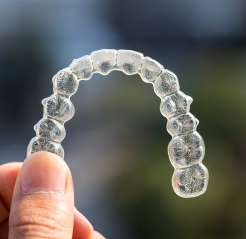 Hand holding a clear aligner