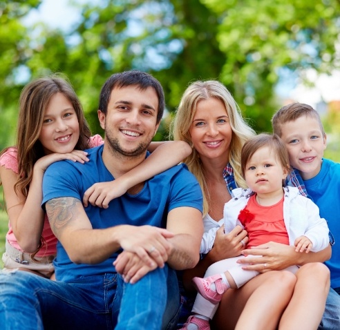 Doctor Arnold sitting outdoors with her husband and three children