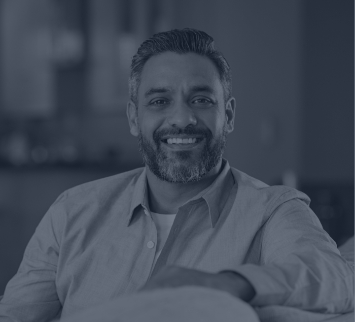 Smiling man sitting on couch after preventive dentistry visit