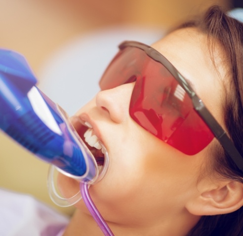 Young woman in dental chair with fluoride trays on her teeth