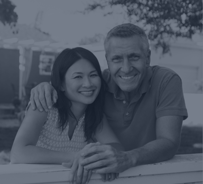 Smiling man and woman standing in their front yard