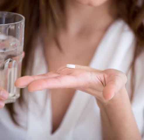 Lady prepares to take pill with water