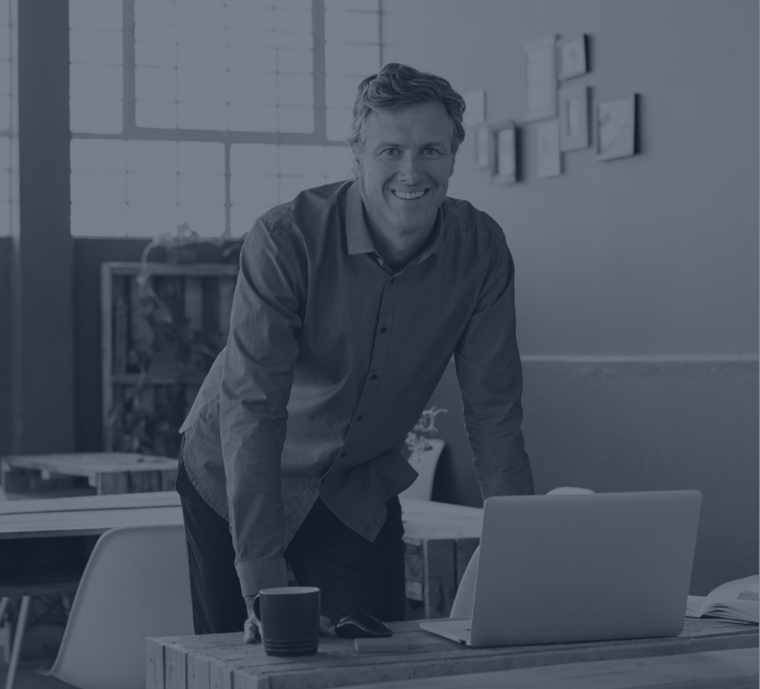 Smiling man getting up from desk with laptop