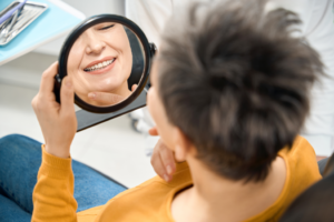 a woman examining her smile in a mirror